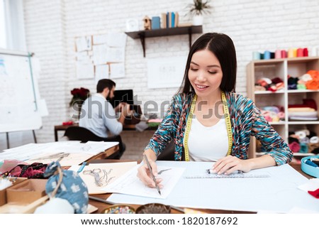 Female fashion designer drawing with ruler on paper. Stylish girl designer draws new sketches for new things in a working studio.