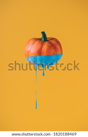 Halloween minimal concept with pumpkin and paint. Creative spooky holiday fun background Royalty-Free Stock Photo #1820188469