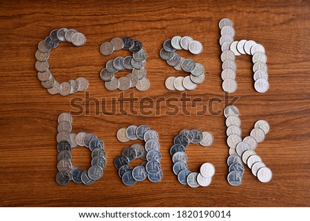The phrase "Cash back", laid out on a wooden surface of modern Russian coins with a face value of one ruble.