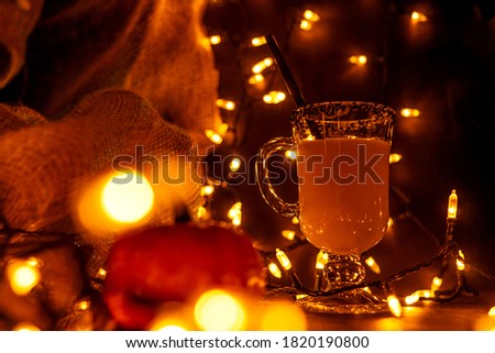 Orange Halloween cocktail and holiday decor on a dark mystical autumn background. Garland and golden bokeh.