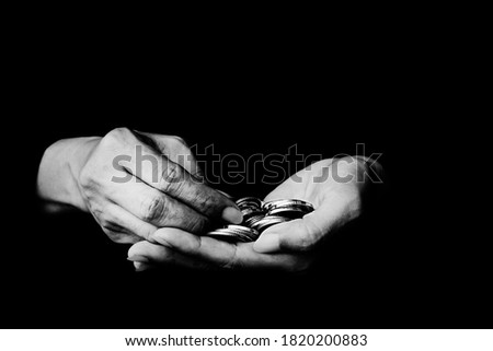 Money coin in hand black and white photo on black background - Black and white photo of coins in old wrinkled hands close-up