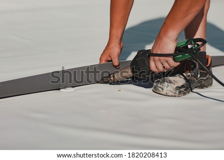Worker welding pvc roof membrane by heater with welder machine Royalty-Free Stock Photo #1820208413