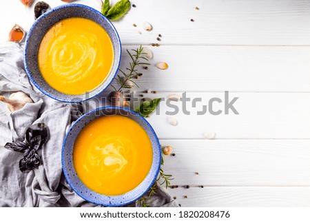Two bowls of pumpkin soup on a white wooden background, top view, copyspace