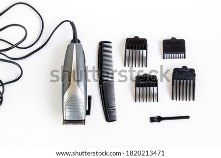 Slim Hair Clipper with stainless steel blades and different size combs of clipper and writing numbers on them on grey background.