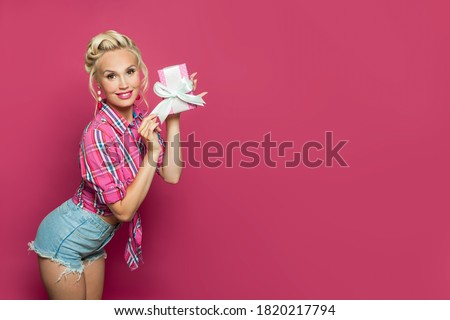 Happy Pin-up woman with gift posing on pink banner background
