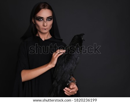 Mysterious witch with raven on black background