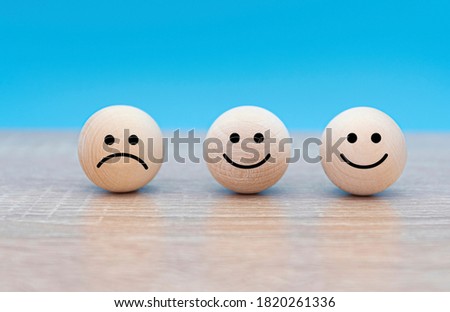 Three wooden faces, happy and sad faces, concept picture about mood of people