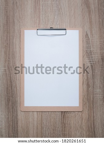 Blank clipboard on wooden desk background.