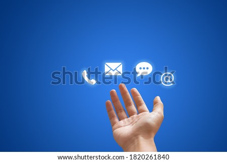Call Center and Contact US Concept : Hand holding and showing contact us icon symbols in blue background.