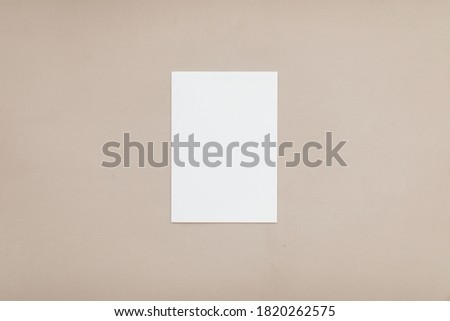 Modern stationery still life. Closeup of blank greeting card mock up scene. Beige table background. Flat lay, top view.
