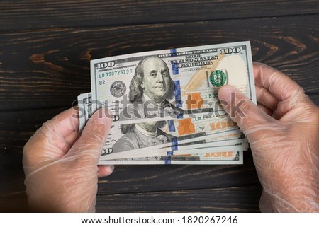 Stack of dollars USA in gloved hands on wooden table