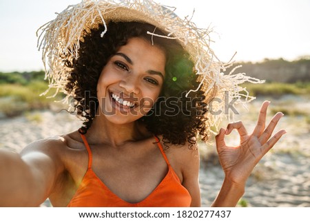 Smiling young african woman taking a selfie at the beach