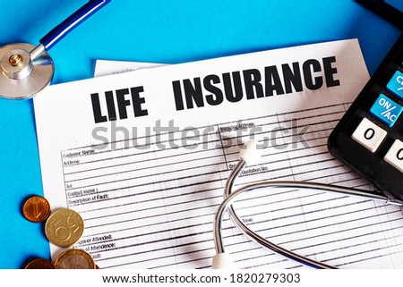 LIFE INSURANCE is written on the insurance policy next to the stethoscope, calculator and coins. Medical and insurance concept