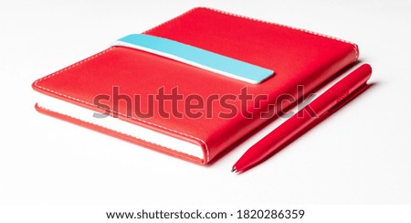 On a white background red notepad and pen close up