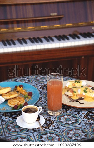 Beautiful healthy breakfast in a restaurant for two. Cheese pancakes, scrambled eggs coffee and juice on a street table