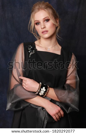 high fashion portrait of young elegant woman. Studio shot. vogue style image for magazine. Portrait of lovely woman wearing fashionable evening dress looking isolated over dark blue fabric background