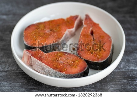 Fresh raw red fish steaks on white plate.
