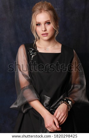 high fashion portrait of young elegant woman. Studio shot. vogue style image for magazine. Portrait of lovely woman wearing fashionable evening dress looking isolated over dark blue fabric background
