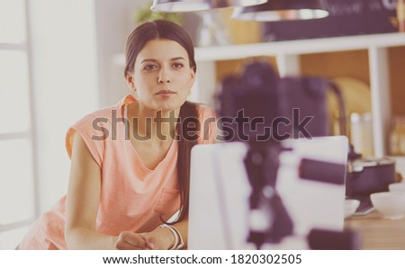Young woman in kitchen with laptop computer looking recipes, smiling. Food blogger concept