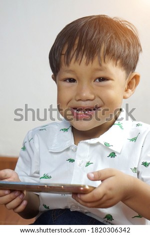 Cute little boy watching cartoons on mobile phone,Preschool kid sititng playing games on smart phone,Child typing or using cell phone while relaxing at home,Select focus                             