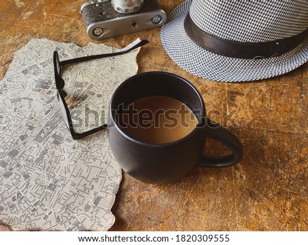 Old camera, hat and cup of coffee on wooden table 