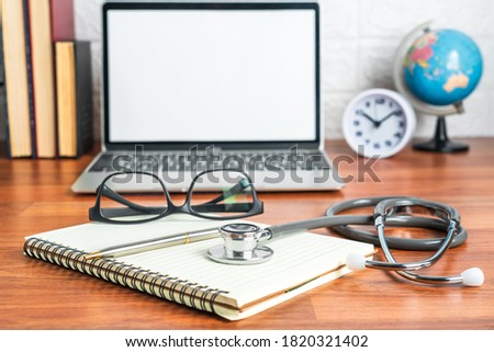 Medical stethoscope for doctor checkup with laptop computer on doctor note pad as medical concept