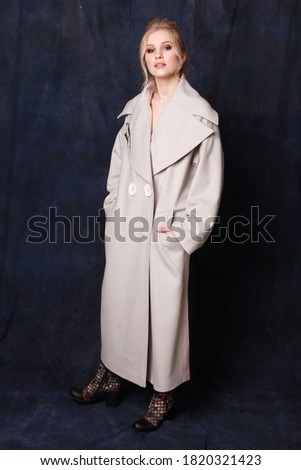 Beautiful, confident and successful woman with make up is posing in stylish coat with bright exclusive accessories (studio shoot of catalogue of fashionable clothes, model demonstrates collection)