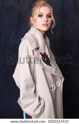 Beautiful, self-contained, confident and successful young woman is posing in a stylish autumn woolen coat (studio shoot of catalogue of fashionable clothes, model demonstrates the collection)