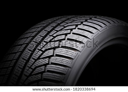 winter tire, driving safety on snowy and icy roads. asymmetric tread pattern. close-up on a black background. Royalty-Free Stock Photo #1820338694