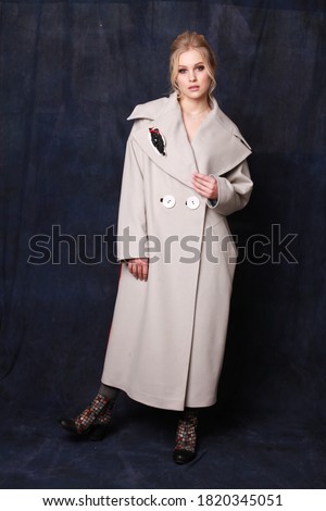 Beautiful, self-contained, confident and successful young woman is posing in a stylish autumn woolen coat (studio shoot of catalogue of fashionable clothes, model demonstrates the collection)
