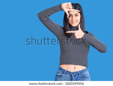 Young beautiful girl wearing striped t shirt smiling making frame with hands and fingers with happy face. creativity and photography concept. 