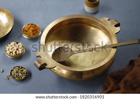Brass vessel,south indian traditional metal vessel named urule ,which is arranged to make payasam or kheer using cashewnut,kismiss and cardamom with grey background Royalty-Free Stock Photo #1820356901
