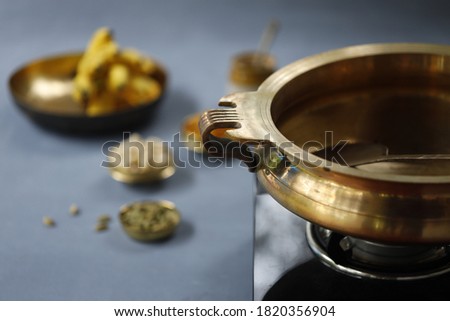 Brass vessel,south indian traditional metal vessel named urule ,which is arranged to make payasam or kheer using cashewnut,kismiss and cardamom with grey background Royalty-Free Stock Photo #1820356904