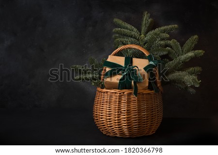 Christmas holiday gift hamper with craft gift and evergreen spice branches on black background. Xmas greeting card with copy space.