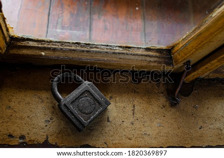 An old padlock lies on an old dirty window sill