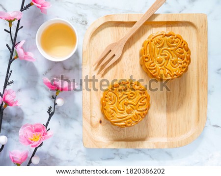Mooncakes on a wooden plate with a cup of tea for Mid-Autumn Festival or Mooncake Festival. Top view.