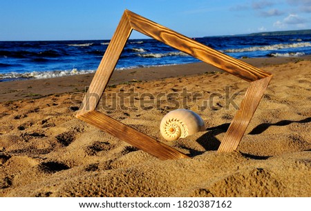 Photo frame and shell on the sand 