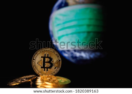 Bitcoin gold coin on globe background and face mask. Current concept of viral impact Elements of this image furnished by NASA.