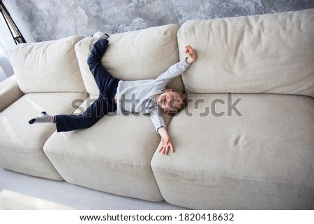 A child is lying on the sofa A cheerful boy is resting