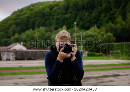 young caucasian
the boy holds a camera and takes amazing pictures. Photography. engaging in photography. job for young people.