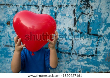 Boy holding an inflatable ball in the form of heart on a blue background