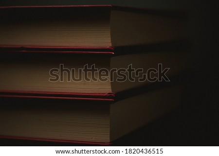 three old red books with yellow pages on black background