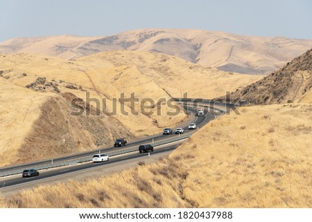 Freeway road with cars crossing the the San Luis Reservoir valleys during dry and hot season, San Luis Creek in the eastern slopes of the Diablo Range of Merced County, California. USA Royalty-Free Stock Photo #1820437988