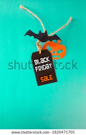 Black Friday and Halloween concept. Black Friday sale tag with bat and jack pumpkin on turquoise with copy space for text or ad