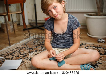 Pretty little girl looks into the camera is engaged in physical labor. Sews together scraps of fabric. Free time hobby. Needlework.