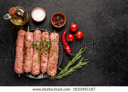 raw Lula kebab on skewers with spices in a black plate on a stone background with copy space for your text Royalty-Free Stock Photo #1820485187
