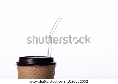 Modern craft disposable paper cup with eco-friendly glass straw isolated on white background. Coffee to go, takeaway hot drinks, coffee shop cafe ads, recycling, reusable tableware concept. Copy space
