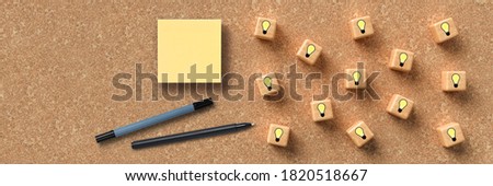 cubes with lightbulb symbols and sticky notes on cork background