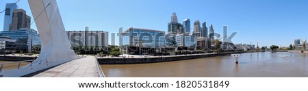 Panoramic view over a modern bridge crossing a canal, the buildings behind and a frigate at Madero Port, Buenos Aires, Argentina