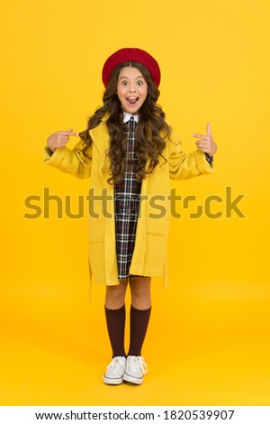 she is so surprised. little girl in coat going to school. education concept. school and fashion. child in pupil uniform. kid in french beret on yellow background. stylish teen college student.